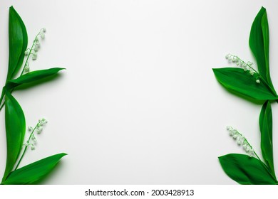Small bouquets of lilly of the valley on the sides as floral borders with copy space. Flat lay with white background.  - Shutterstock ID 2003428913