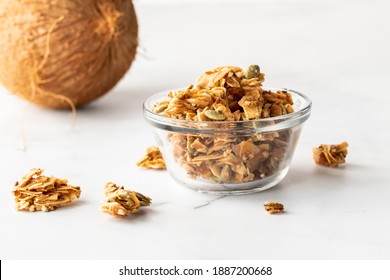 A small bowl filled with coconut clusters against a bright background.