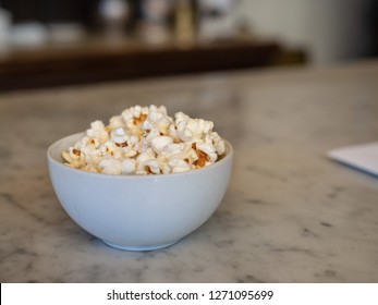 Small bowl of fresh popcorn sitting on marble counter with menu paper