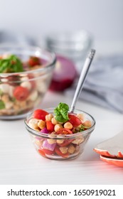 A Small Bowl Of Garbanzo Bean Salad Garnished With Basil, Ready For Eating.