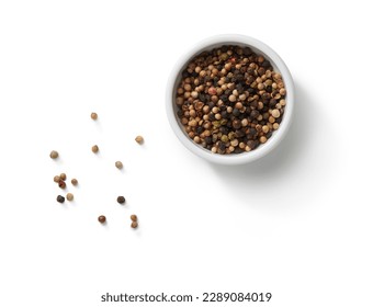 small bowl of peppercorns and scattered peppercorns top view, isolated on white background