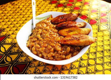 A Small Bowl Of Porridge Beans Served With Nigerian Fried Plantain On A Yellow Colorful Pattern Background