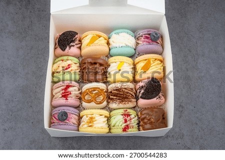 Small box with assorted macarons. A small dessert box filled with assorted colorful macarons arranged in tight rows