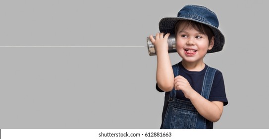 A small boy attached a telephone from a tin can to his ear
