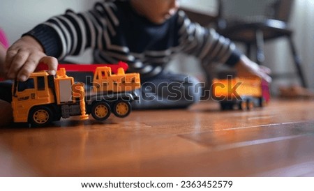 Small boy clashing trucks together seated on floor. Male child hitting toys plays with objects