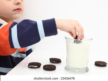 Small Boy Dunking Cookies In Milk.