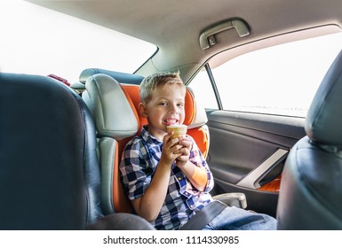 A Small Boy Eating Ice Cream, Sitting Strapped In The Car Seat.