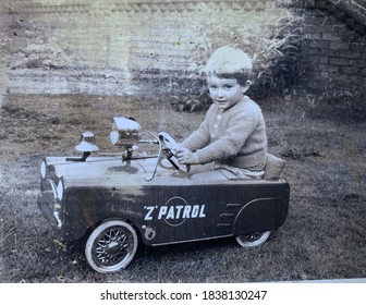 Small boy in a hand knitted cardigan and shorts in a Police pedal car CIRCA 1964. He later went on to become a London Policeman. - Shutterstock ID 1838130247