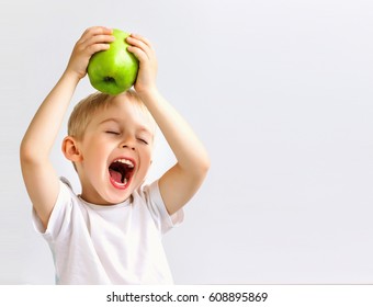 small boy holds a big green apple, healthy food and vitamins, smiling, white background, soft focus