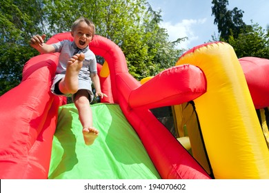 Small boy jumping down the slide on an inflatable bouncy castle - Powered by Shutterstock