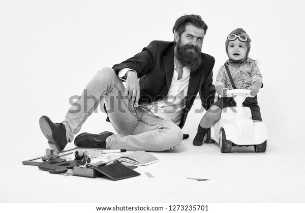 small boy kid driver or pilot sitting on\
plastic toy cat in stylish shirt with bearded man father with beard\
near school appliances of blackboard letter pen and paper isolated\
on white background