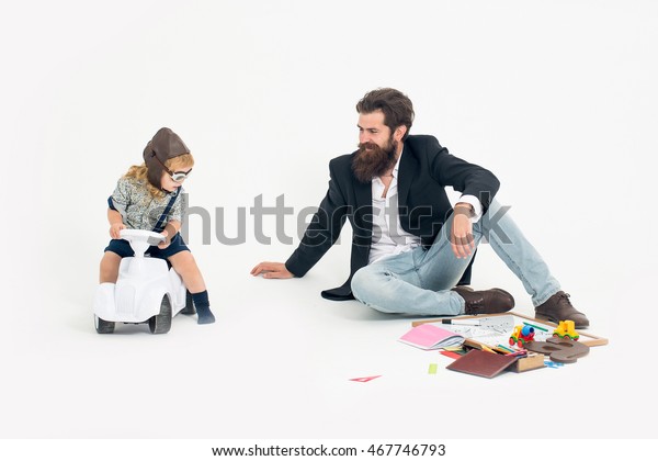 small boy kid driver or pilot sitting on\
plastic toy cat in stylish shirt with bearded man father with beard\
near school appliances of blackboard letter pen and paper isolated\
on white background