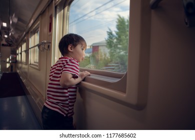 small boy looking in the window of passenger train