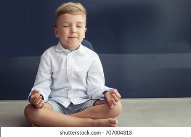 Small Boy Meditates In Lotus Position. Child Practices Yoga Breathing Exercise With Eyes Closed. 