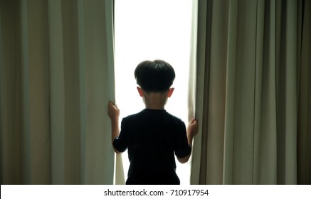 Small boy opening curtains