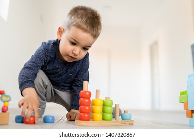 Small Boy Playing With Wood Brain Teaser Toys On The Wooden Floor At Home