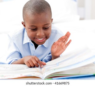 Small boy reading a book on his bed