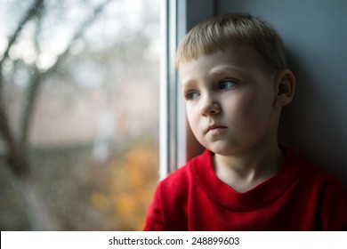 small boy sitting near window and thinking about something