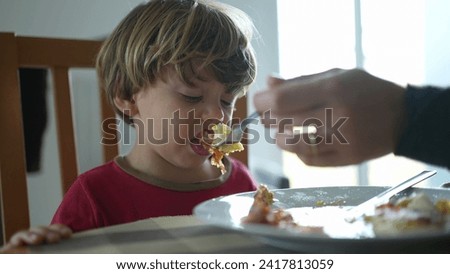 Small boy spitting food out during lunch time. Child not wanting food, feeling disgust