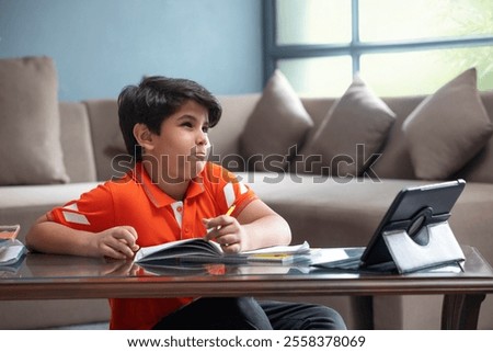 A SMALL BOY THINKING SERIOUSLY WHILE ATTENDING ONLINE CLASS