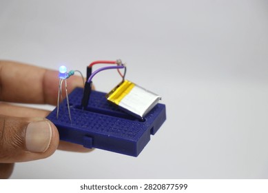 Small breadboard with glowing LED and the lithium polymer battery