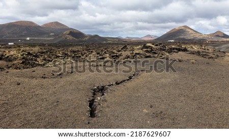 A small break or crack in the ground against the backdrop of volcanoes, Lanzarote, Canary Islands, Spain