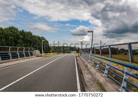small bridge with lampposts  crossing over a freeway in a rural surrounding and under a beautiful cloudy sky. [[stock_photo]] © 