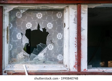 Small Broken Window With Red Frame And Window Shades Torn Apart. Detail Of An Old Abandoned House, Falling Apart.