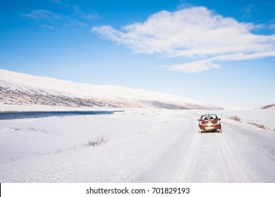 Small Brown Car On Roadtrip In Iceland In Snow Ice Winter Under Blue Sky