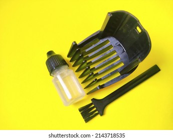 Small Brush,comb Guard Of Hair Clipper And A Bottle Of Grease Isolated On Bright Yellow Background. Selected Focus