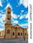 A small building with a blue door sits in front of a large Mosque with a tall tower in Nicosia, Cyprus. Beautiful street with old architecture in Nicosia, Cyprus.