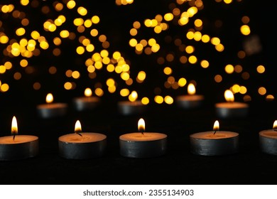 Small burning candles on the table on black background
