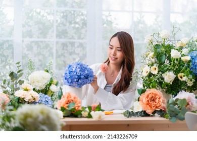 Small business. Asia Female florist smile arranging flowers in floral shop. Flower design store. happiness smiling young lady making flower vase for customers, preparing flower work from home business