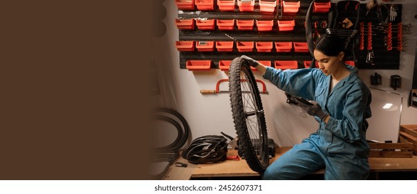 Small business bike repair. Young caucasian woman wearing uniform, uses mobile phone technology, takes notes in bicycle workshop. Banner. Copy space - Powered by Shutterstock