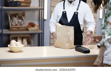 Small business concept senior female customer shopping bread and desserts at the local bakery professional baker serving his customer at his own bakery - Powered by Shutterstock