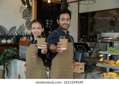 Concepto de estilo de vida de inicio de esposo y esposa de pareja de negocios Pequeños, hombre y mujer asiáticos con delantal de pie frente al mostrador que sostiene la taza de café y el letrero abierto, sociedad del propietario de la cafetería