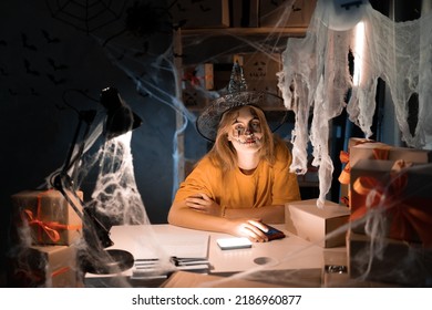 Small Business Dropshipping. Young Female Businesswoman In The Workplace In A Witch Costume Sits In A Warehouse At Home. Big Sale Concept For Halloween. Portrait