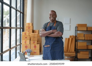 Small Business Entrepreneur Startup SME Independent, African American male businessman standing with arms crossed and smiling confidently. Ecommerce concept Product packing, delivery. - Powered by Shutterstock