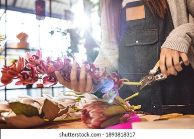 Small business. Female florist unfocused in flower shop. Floral design studio, making decorations and arrangements. Flowers delivery, creating order. Woman florist arranging plants in flower shop - Powered by Shutterstock