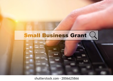 Small Business Grant - A Man Writes On A Laptop Keyboard. Small Business Investment Search And Support Concept