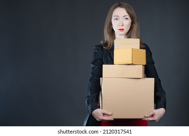 Small Business Owner Concept. Woman With Cardboard Boxes. Girl Owns Her Own Business. Small Business Leader. Cardboard Parcels In Hands Of Businesswoman. Girl On Black. Boxes Metaphor Online Orders