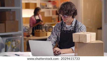 Small business owner or entrepreneur doing e-commerce business on internet. Male manager of online store warehouse working on laptop accept orders