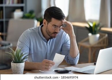 Small business owner experiences financial crisis, high costs, bank debt, money overspend concept. Man sitting at desk looks at laptop screen holding receipt feels desperate after calculating expenses - Shutterstock ID 1854695974