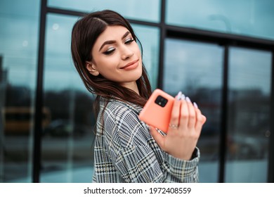 Small Business Owner Office Worker Woman Standing Outside Building With Mobile Phone Make Selfie Video Chat. Female Mexican Latin American Successful Executive Girl Hold Gadget
