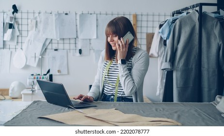 Small Business Owner Is Ordering Fabric For Her Tailor's Shop With Mobile Phone And Working With Laptop. Woman Is Talking And Typing Simultaneously. Modern Means Of Communication Concept.