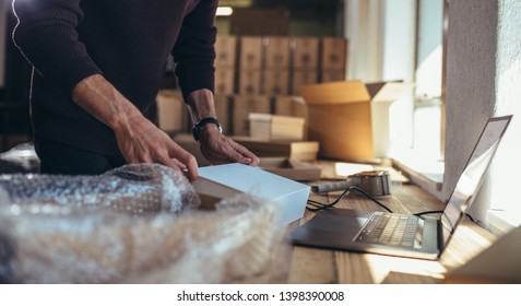 Small business owner packing in the cardbox at workplace. Cropped shot of man preparing a parcel for delivery at online selling business office.