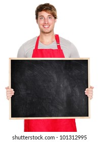 Small Business Owner Showing Blank Empty Blackboard Sign Wearing Apron. Handsome Young Shop Owner Man Isolated On White Background Smiling Happy.