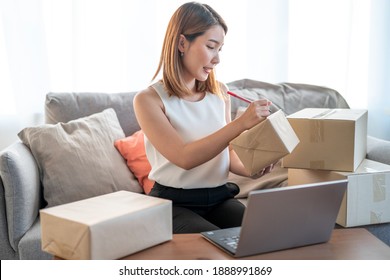 The Small Business Owner Smiles And Writes Information On The Parcel, Online Trading Ideas And Product Delivery.