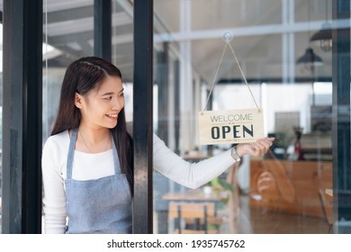 Small Business Owner Smiling While Turning The Sign For The Reopening Of The Place After The Quarantine Due To Covid-19. Close Up Of Woman Hands Holding Sign Now We Are Open Support Local Business.