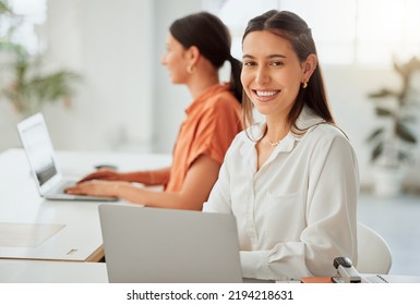 Small Business Owner Or Startup Entrepreneur Working On A Laptop In The Office With A Colleague In The Background. Typing An Email Or Planning Ideas At Her Desk In A Modern And Creative Company